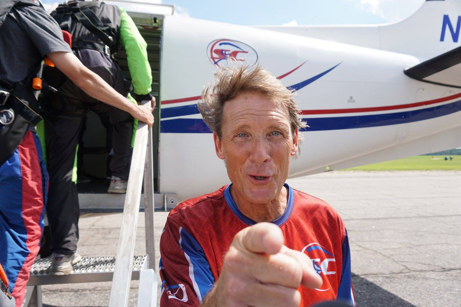 Airplane ground crew points at camera as skydivers load 