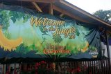 A large banner reads "Welcome to the Jungle 2015" with tropical graphics and the text "Skydive Carolina Fest." A person stands on the right side of the banner. Red flowers are visible at the bottom.