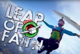 A skydiver in mid-air wears a colorful outfit and helmet, with a plane above. Text on the image reads "Leap of Faith" and features a logo for Operation Christmas Child with a gift and an airplane. Clouds and a blue sky are visible in the background.