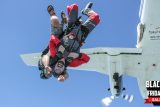 Two people in skydiving gear jumping out of an airplane, with one wearing goggles and a helmet. They're in a tandem skydive position against a clear blue sky. A "Black Friday Sale" banner is in the bottom right corner.