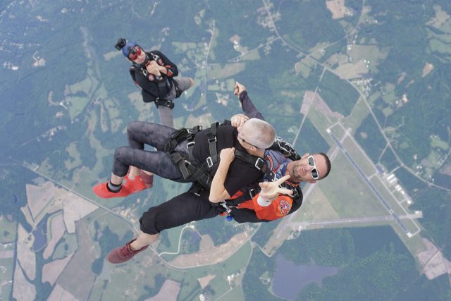 Tandem skydivers exit from airplane with videographer