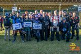 A group of people wearing skydiving gear stand together under a shelter. Some hold signs reading "Thank You!" and "Sponsor Skydive Carolina." They appear cheerful and ready for an event.